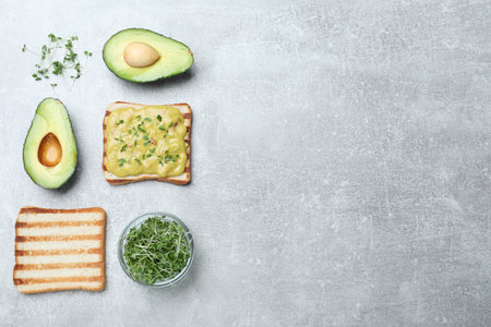 Delicious sandwich with guacamole and microgreens on gray table, flat lay. Space for textの写真素材