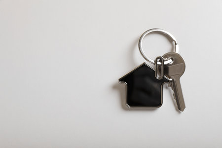 Key with trinket in shape of house on white background, top view and space for text. real estate agent servicesの写真素材