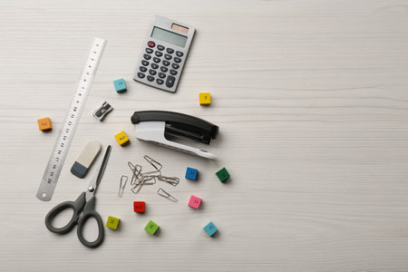 Colorful cubes with numbers and stationery on white wooden table, flat lay. Space for text