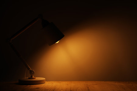 Stylish modern desk lamp on wooden table at night, space for textの写真素材