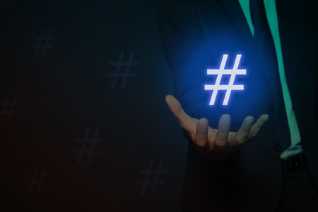 Hashtag concept. Man holding sign on dark background, closeup with space for textの写真素材