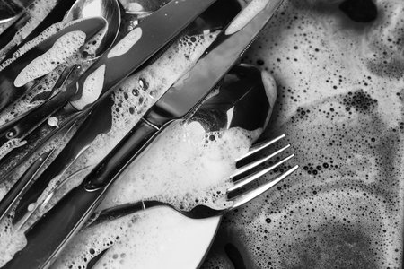 Washing silver spoons, forks and knives in foam, above viewの写真素材