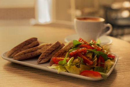 Plate of delicious toasts with salad and coffee cup on wooden table in cafe, closeupの写真素材