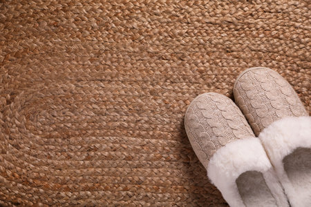 Pair of warm stylish slippers on wicker carpet, top view. Space for textの写真素材