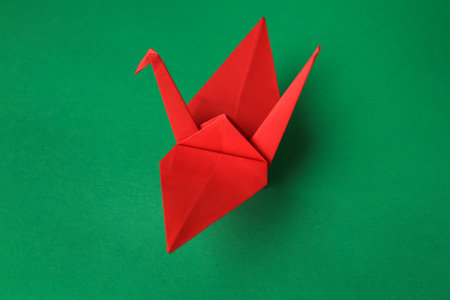 Red paper origami crane on green backgroundの写真素材