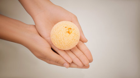 Woman holding bath bomb on light background, closeup. Space for textの写真素材