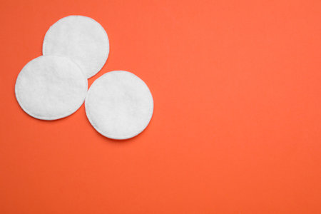 Clean cotton pads on orange background, flat lay. Space for textの写真素材