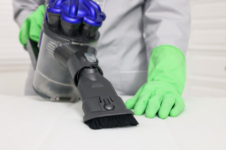 Woman in gloves disinfecting mattress with vacuum cleaner indoors, closeupの写真素材