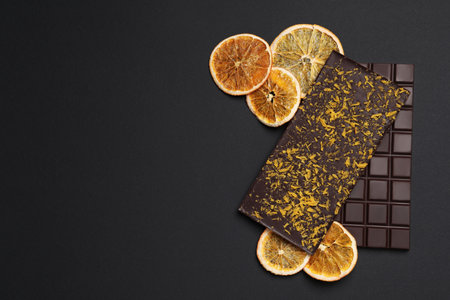 Chocolate bars with freeze dried orange on black background, flat lay. Space for textの写真素材