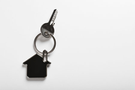 Key with trinket in shape of house on white background, top view and space for text. real estate agent servicesの写真素材