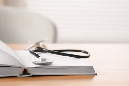 Book and stethoscope on wooden table indoors, space for text. doctor educationの写真素材