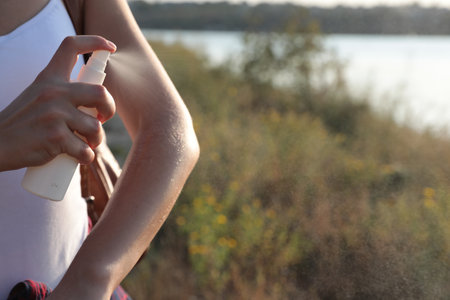 Woman applying insect repellent onto arm outdoors, closeup. Space for textの写真素材
