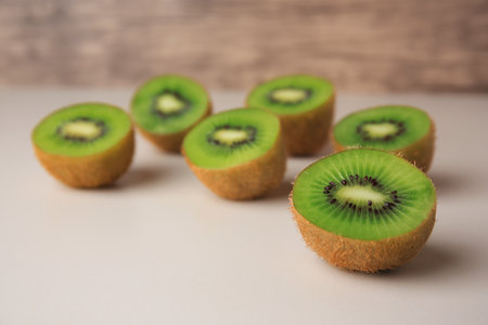 Halves of fresh kiwis on beige table, closeup. Space for textの写真素材