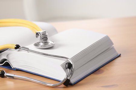 Book and stethoscope on wooden table indoors, space for text. doctor educationの写真素材
