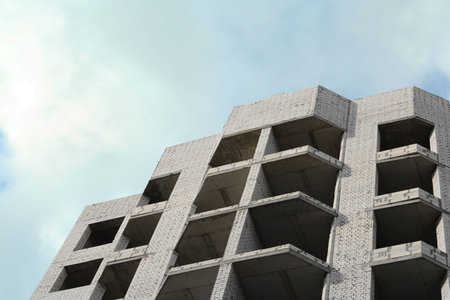 Construction site with unfinished building under cloudy sky, low angle view