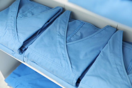 Light blue medical uniforms on white rack, closeupの写真素材