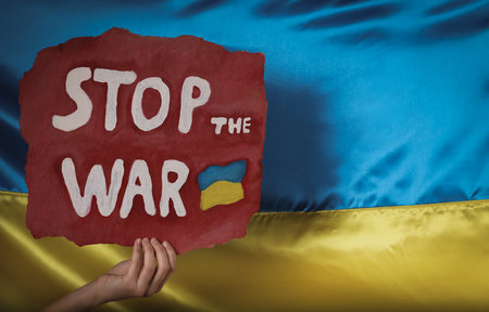 Woman holding poster with words Stop the War near Ukrainian flag, closeup. Space for textの写真素材