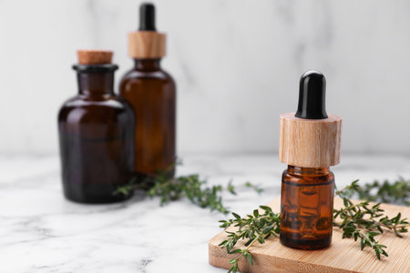 Thyme essential oil on white marble table, space for textの写真素材