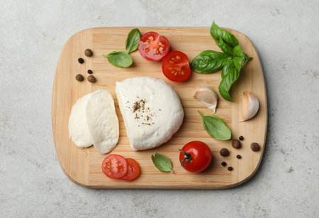 Delicious mozzarella with tomatoes and basil leaves on light gray table, top view