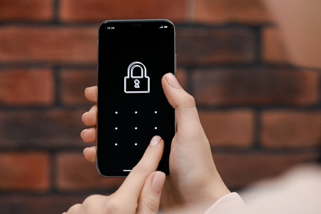 Woman unlocking smartphone with blocked screen indoors, closeupの写真素材