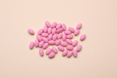 Many pink dragee candies on yellow background, flat layの写真素材