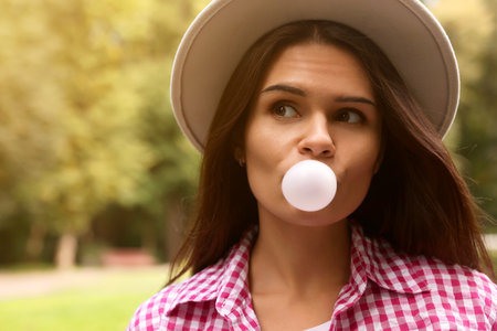 Beautiful young woman blowing chewing gum outdoorsの写真素材