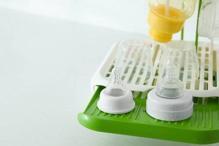 Dryer with baby bottles and nipples after sterilization on white table. Space for textの写真素材