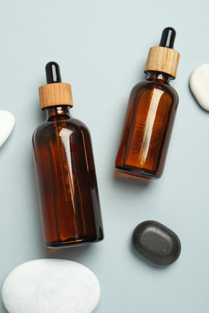 Flat lay composition with bottles of face serum and spa stones on light gray backgroundの写真素材