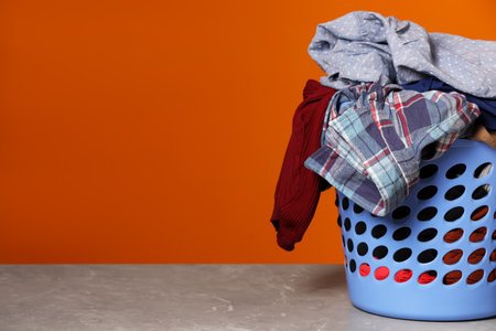 Laundry basket with clothes near orange wall. Space for textの写真素材