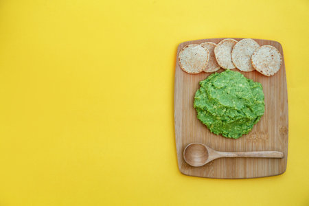 Delicious guacamole made of avocados and nachos on yellow background, top view. Space for textの写真素材