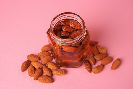 Jar with almonds and honey on pink backgroundの写真素材