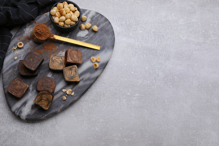 Flat lay composition with tasty chocolate candies and nuts on light gray table. Space for textの写真素材