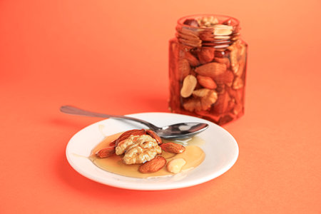Different tasty nuts with honey on orange backgroundの写真素材