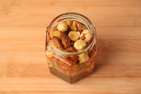 Various nuts and honey in jar on wooden table, above viewの写真素材