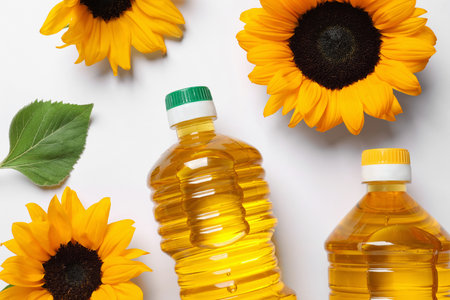 Bottles of cooking oil and sunflowers on white table, flat layの写真素材