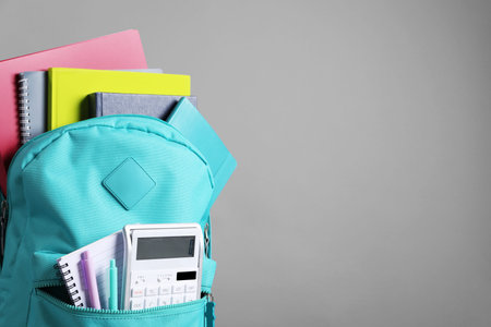 Turquoise backpack and different school stationery on gray background, space for textの写真素材