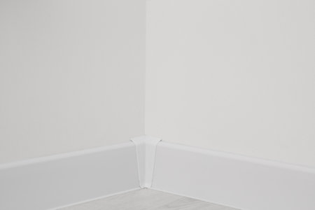Corner of white wall with baseboard indoorsの写真素材