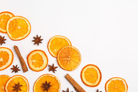 Flat lay composition with dry orange slices, anise stars and cinnamon sticks on white background. Space for textの写真素材