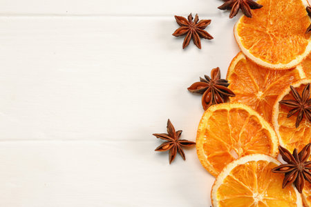 Dry orange slices and anise stars on white wooden table, flat lay. Space for textの写真素材