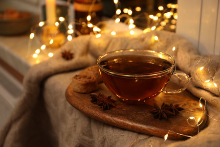 Glass cup of aromatic anise tea on wooden board indoors, bokeh effectの写真素材