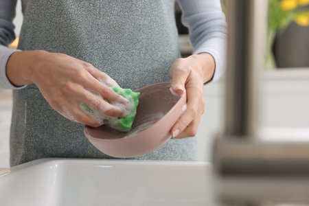 Woman washing plate above sink in modern kitchen, closeupの写真素材