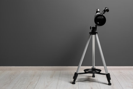 Tripod with modern telescope near grey wall. Space for textの写真素材