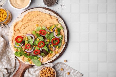 Tortilla with hummus and vegetables on white table, flat lay. Space for textの写真素材