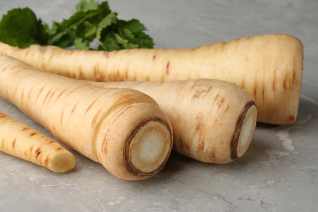 Many fresh ripe parsnips on grey marble table, closeupの写真素材