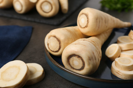 Whole and cut parsnips on black table, closeupの写真素材
