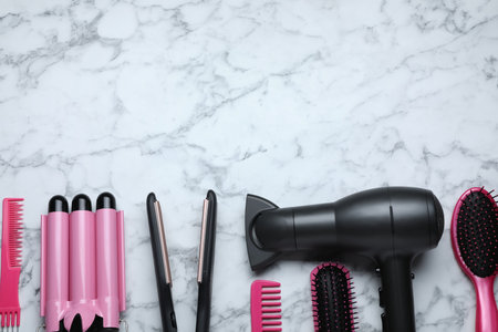 Flat lay composition of professional hairdresser tools on white marble table, space for textの写真素材