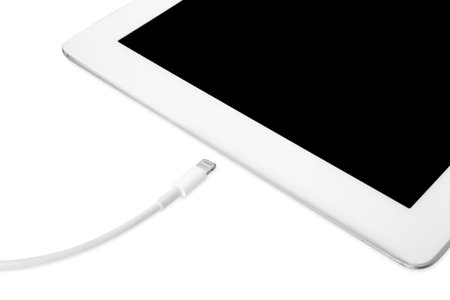 USB cable with lightning connector and tablet on white background