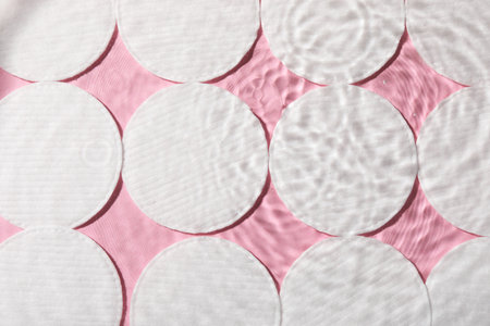 Many cotton pads in water on pink background, flat layの写真素材