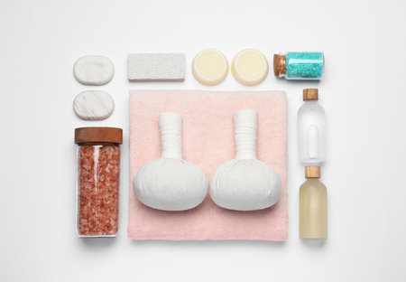 Flat lay composition with herbal massage bags and other spa products on white backgroundの写真素材
