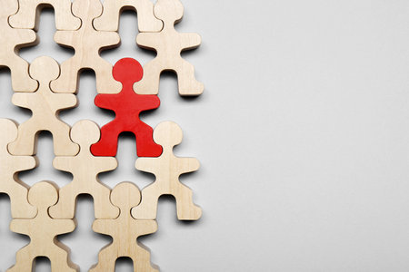 Red figure among wooden ones on light grey background, flat lay with space for text. Recruiter searching employeeの写真素材